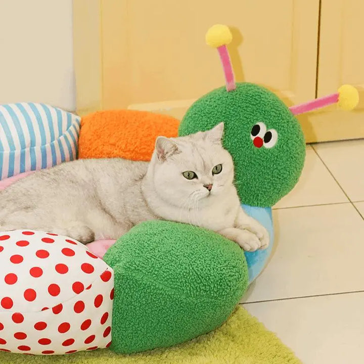 "Green caterpillar-shaped pet bed with colorful details, providing comfort and fun for pets."