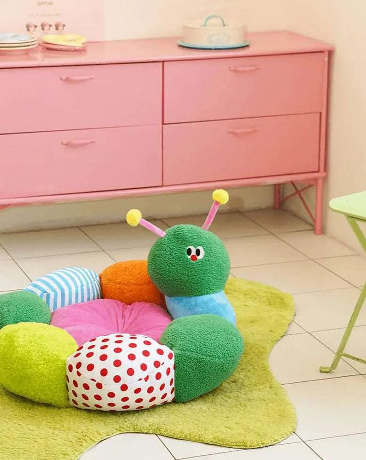 "Green caterpillar-shaped pet bed with colorful details, providing comfort and fun for pets."