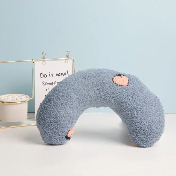 Small U-shaped pillow in plush fabric, providing head and neck support for puppies inside crate.