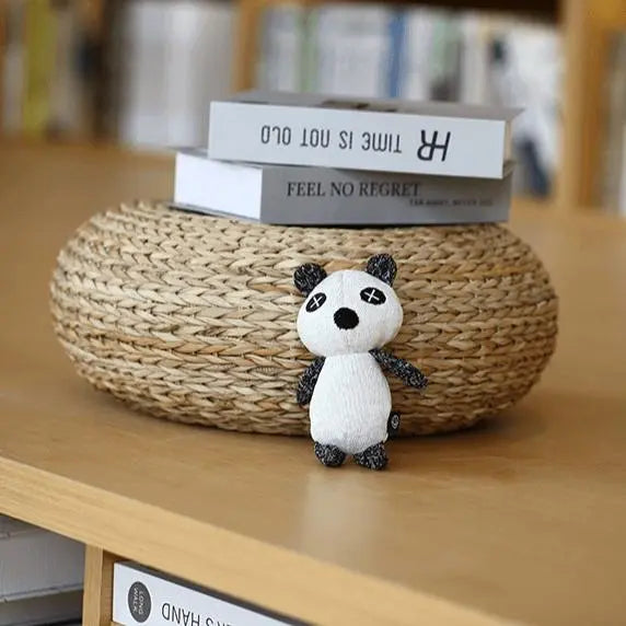 A plush toy designed for dogs, featuring a black and white panda shape with distinctive X-shaped eyes. Made from soft, knitted fabric, the toy is lightweight and cuddly, suitable for small to medium-sized dogs. It has a squeaker embedded inside for interactive play and is crafted with pet-safe materials for durability and comfort. The toy's design is both visually appealing and functional, promoting dental health and reducing anxiety through engaging play.